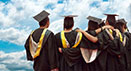 Group of students with graduation caps and gowns on looking to blue sky